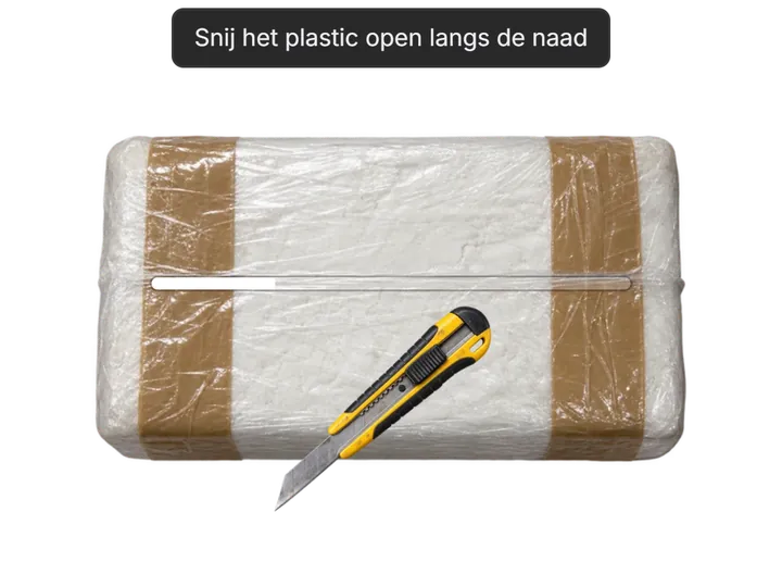 Utility knife slicing the plastic of a taped block along its seam