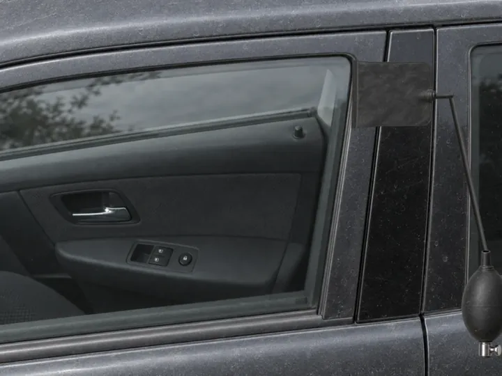 Side of a dark grey car door with the window frame where the air wedge goes in